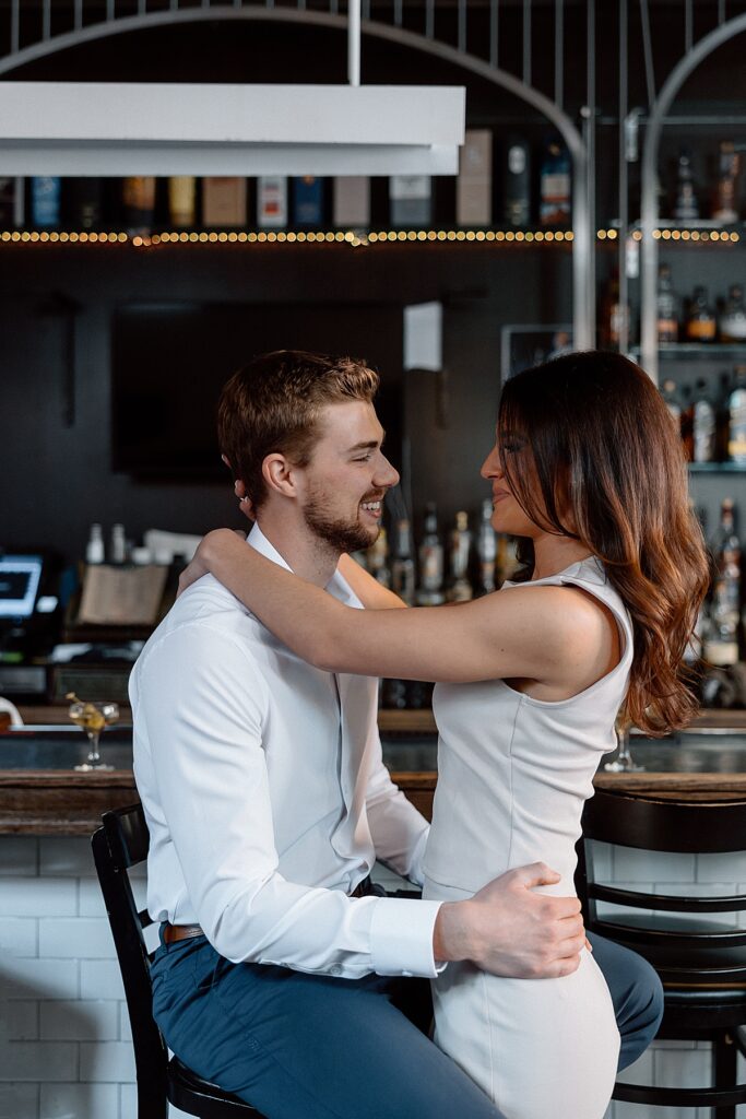 Couple sitting at Philadelphia bar smiling during their engagement photos by Kristy Hoadley
