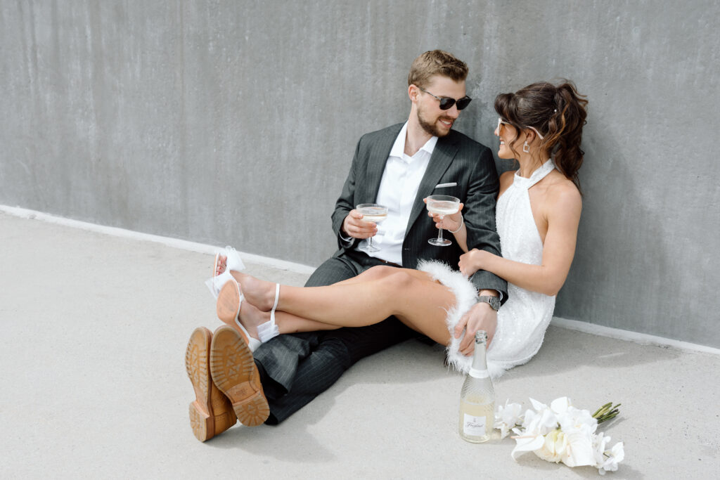 Couple sitting in a parking garage drinking champagne during editorial wedding shoot in Philadelphia